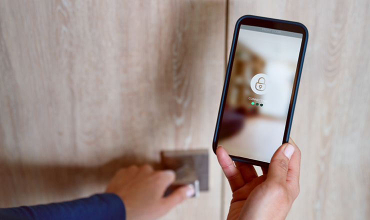 Eigene App und Smart-Home-System Ein Smartphone neben einer Einganstüre gehalten